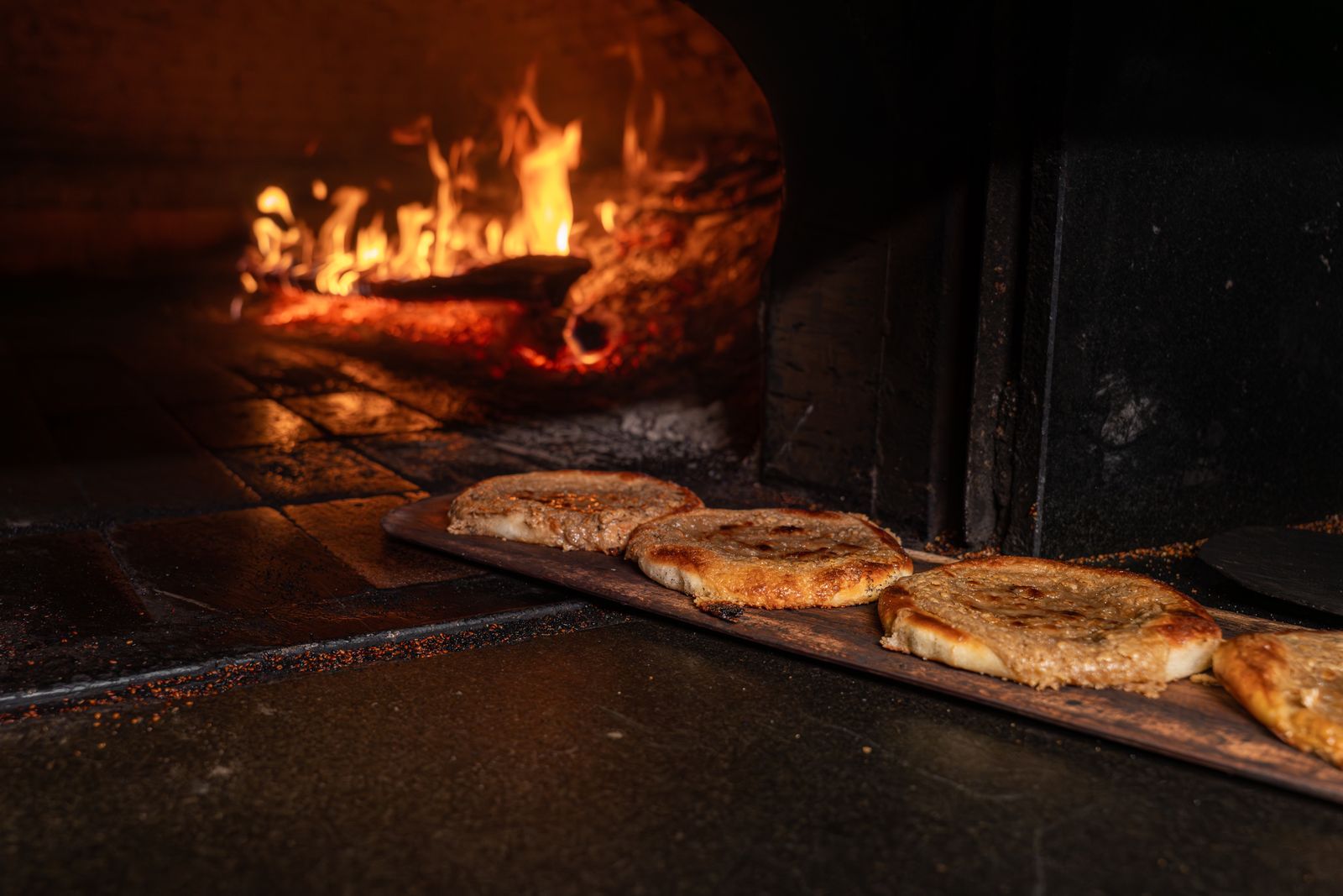 Delicious flatbreads baking in a traditional wood-fired oven, highlighting rustic culinary techniques.